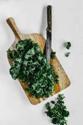 close up shot of chopped kale on a wooden chopping board